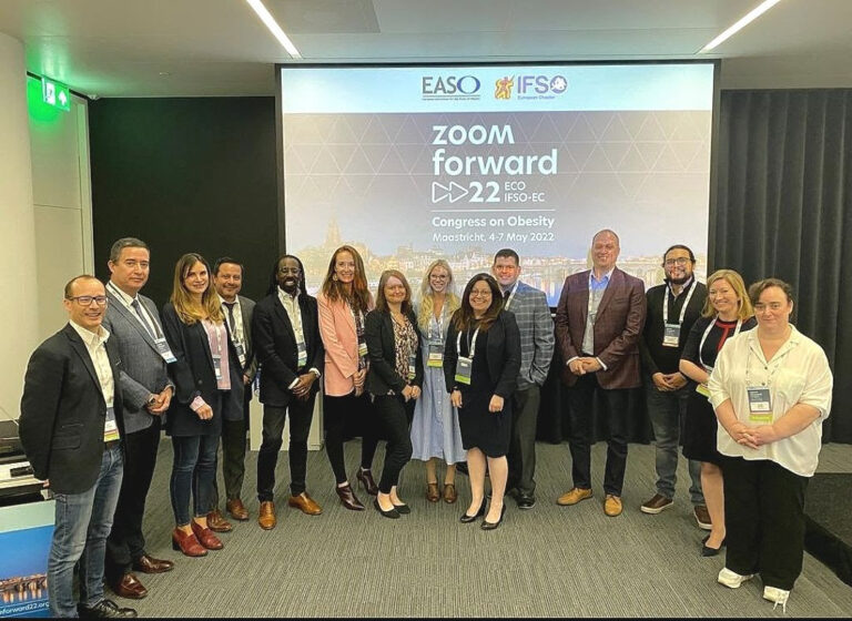 Group of professionals posing in front of a presentation screen at the easo and ifso conference.