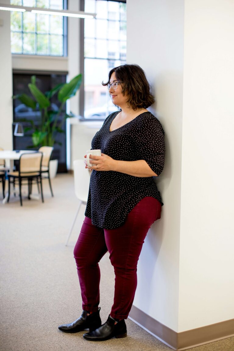 A woman is standing against a wall alone