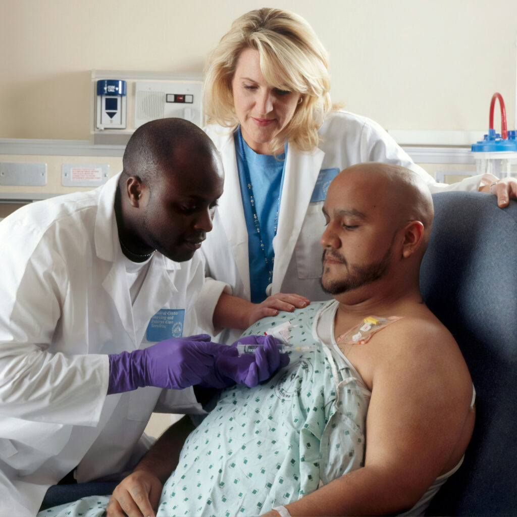 A man is being examined by a doctor with a stethoscope. He is wearing a hospital gown