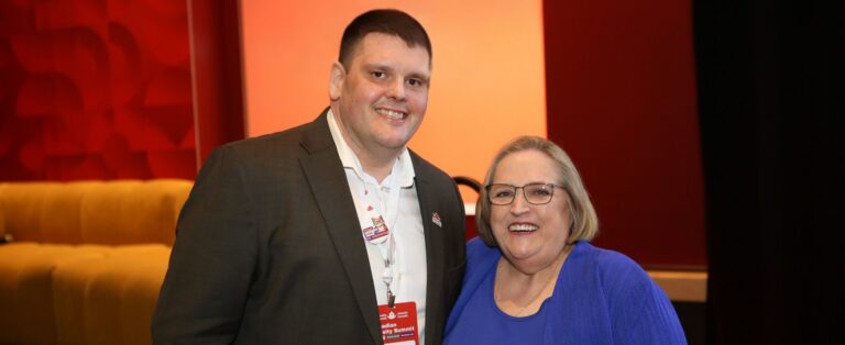 Dr. Ian Patton, Director of Advocacy and Public Engagement at Obesity Canada with Patty Nece in front of a large stage.