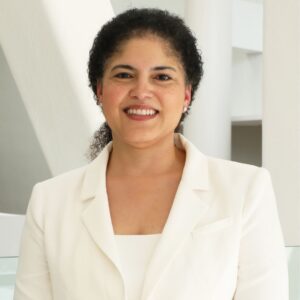 Dr. Cynthia Maxwell smiles at the camera while wearing a white blazer in a bright indoor setting.